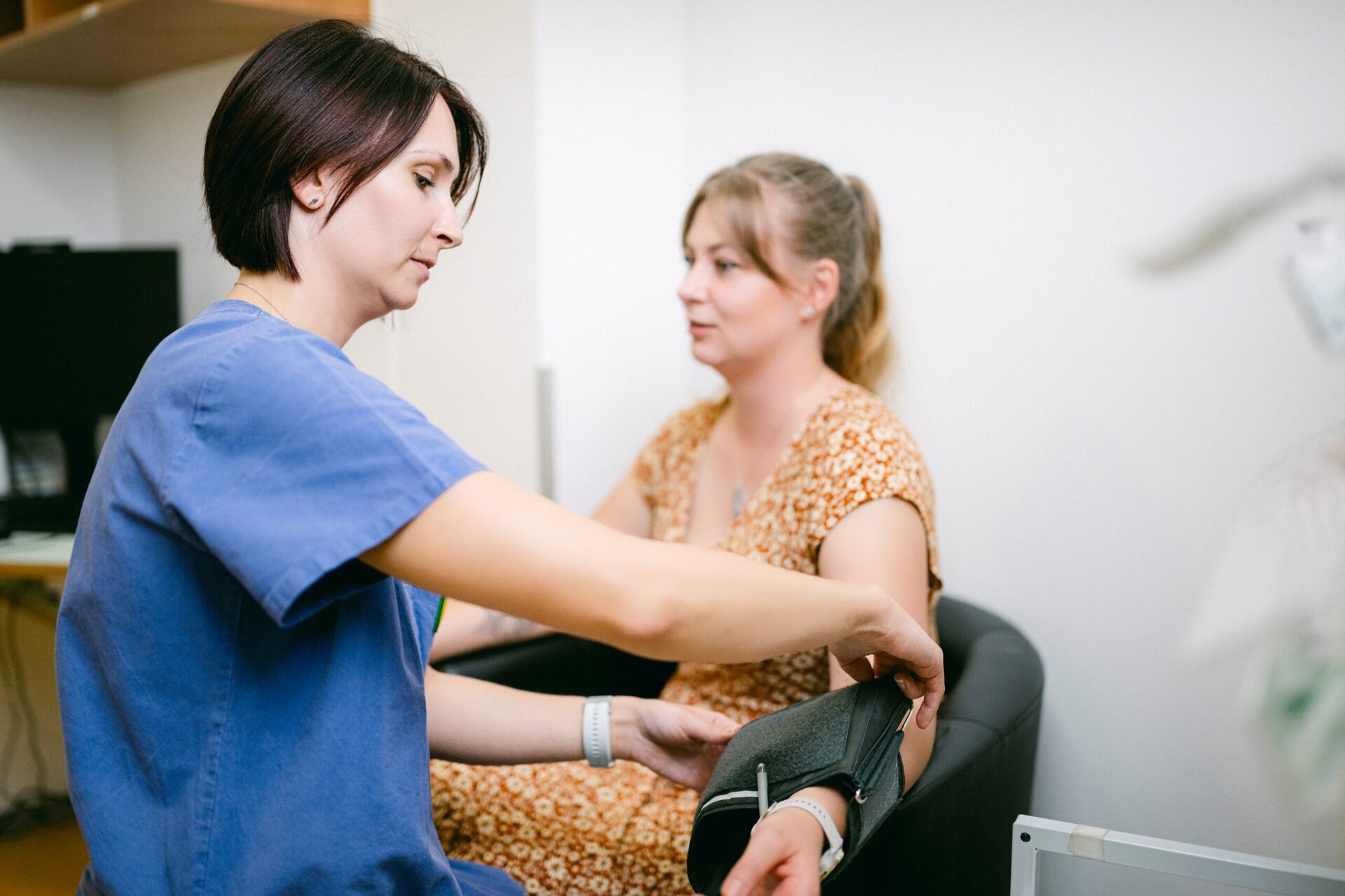 Eine MFA misst den Blutdruck einer Patienten mit einer Manschette.